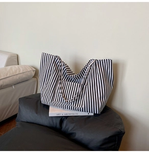 Detail view of a large striped canvas tote bag with an external pocket for daily use