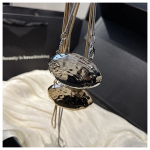 Détail du mini sac en forme de coquillage avec texture martelée et chaînes serpent