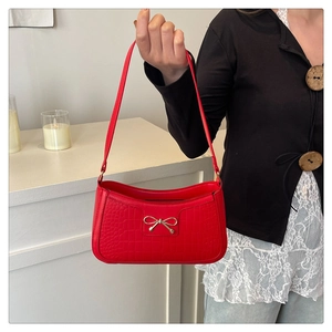 Détail du sac sous le bras rouge effet croco avec boucle dorée porté par un modèle