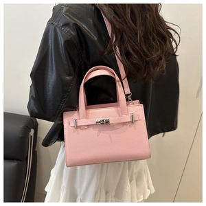 Detailed view of pink lychee texture leather handbag with silver lock worn by a model