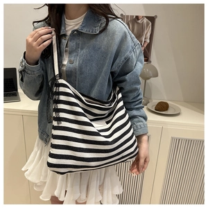 Detail of canvas tote bag featuring black and white stripes and delicate lace strap accent