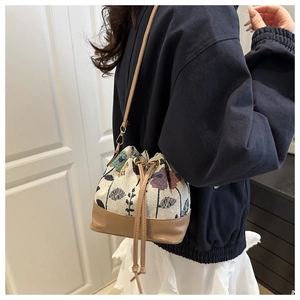 Close-up of floral canvas bucket bag with leather drawstring and shoulder strap detail