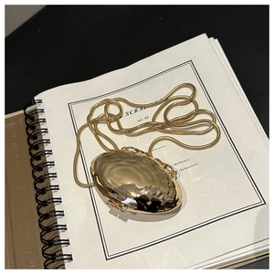 Macro detail of gold wavy metal shell bag on a notebook showing polished mirror finish