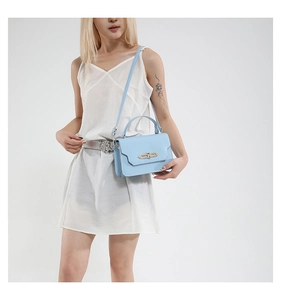 Blue crossbody bag shown on a model in a white dress featuring a gold hardware buckle