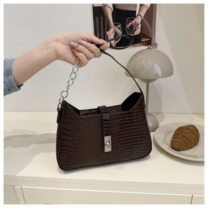 Detail of dark brown crocodile pattern PU leather handbag with silver metallic twist lock
