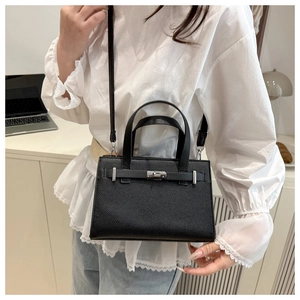 Detail of lychee pattern leather handbag with silver twist lock and handle on model