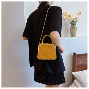Detailed macro view of yellow box handbag featuring floral embossing and gold chain strap