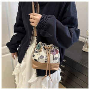 Close-up of ethnic bucket bag with floral embroidery and brown leather shoulder strap