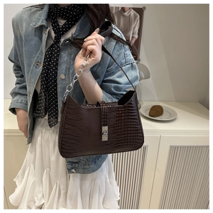 Detailed view of dark brown croc-embossed underarm bag with silver metallic twist lock