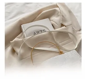 Close-up of white lace embroidery with butterfly patterns and gold handle on crossbody bag