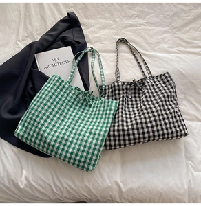 Detail of plaid tote bag featuring checkered pattern and decorative bow tie on handles