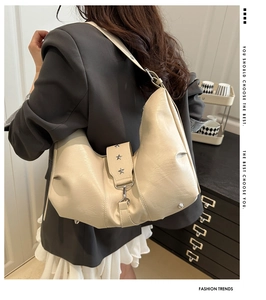 Detail of a beige half-moon hobo bag with three silver star studs on the flap