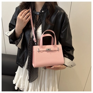 Side view of a pink pebbled leather handbag with silver clasp on a model's arm