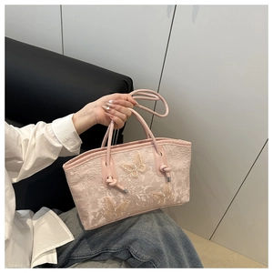 Close-up of pink lace tote bag featuring 3D butterfly appliques and slim leather handles