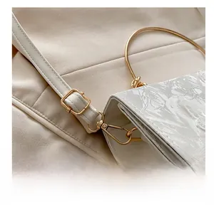 Detail of adjustable gold buckle and white leather strap on lace crossbody bag