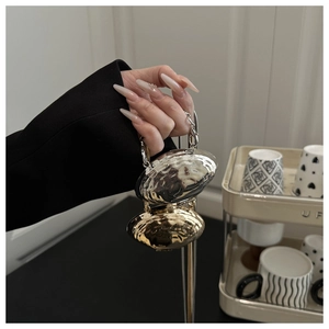 Détail de pendentifs galets martelés or et argent tenus à la main avec chaînes fines