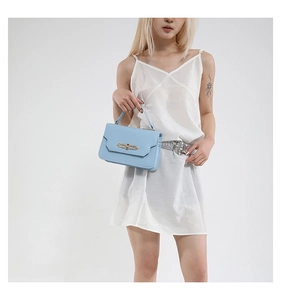 Close-up of light blue leather handbag with gold metal clasp on white silk dress
