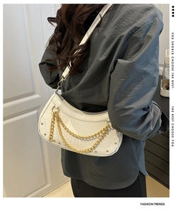 Détail du sac croissant blanc motif crocodile avec chaîne dorée sur l'épaule du mannequin