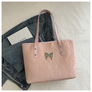 Detailed shot of pink tote bag with shiny crinkled texture and silver butterfly emblem