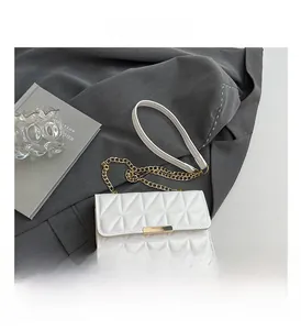 Detail of white quilted handbag featuring gold metal clasp and chain strap on fabric