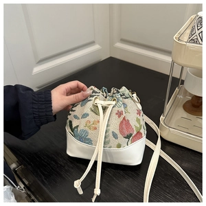 Close-up of ethnic bucket bag featuring floral jacquard and white leather patchwork