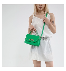 Detail of a bright green leather handbag featuring a striking gold metal clasp and thin strap