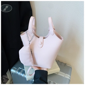 Detail of light pink bucket bag in pebble leather with leaf charm and metal chain