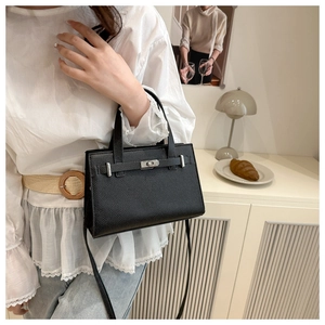 Close-up of a black lychee grain leather handbag with silver hardware and Kelly style clasp