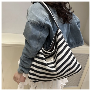 Classic black and white striped canvas tote bag shown worn on shoulder by model