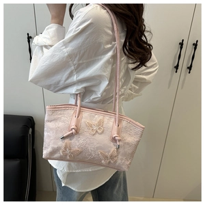 Detailed macro view of pink floral lace fabric and 3D butterfly embroidery on tote bag