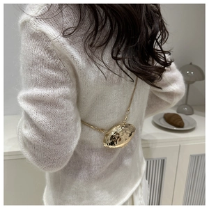 Detail of a mini gold shell-shaped crossbody bag with metallic ripples and chain strap
