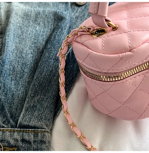 Detailed view of pink quilted mini handbag with gold chain strap and stitching detail