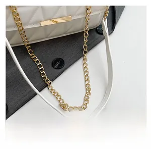 Detail of white quilted crossbody bag showing gold chain strap and metal hardware