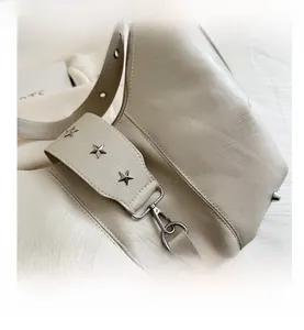 Close-up of cream crossbody bag featuring silver star studs and lychee texture