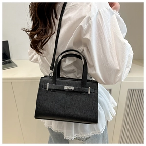Close-up of black lychee grain leather handbag with silver clasp and top handles