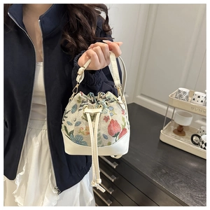 Detailed shot of ethnic floral jacquard bucket bag with drawstring and white leather base
