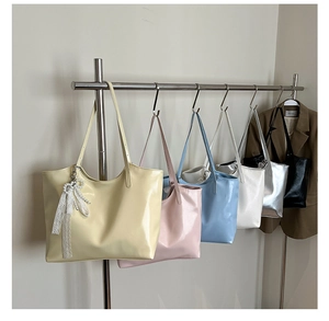 Detail of colorful faux leather tote bags with lace bows and pearl charms on hangers