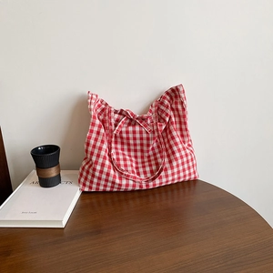 Red gingham tote bag with bow tie detail on a wooden table for a stylish daily look