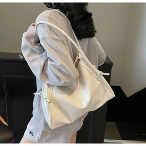 Detail der weißen glänzenden Ledertasche mit Kordelzug-Knoten an der Modelschulter