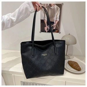Detailed view of the black tote bag featuring elegant embossed floral patterns and label