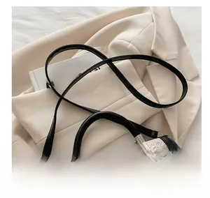 Detail of adjustable black leather strap and silver buckle on a woven contrast handbag