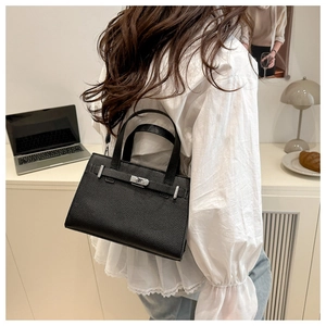 Close-up of black lychee grain leather handbag with silver lock shown in a lifestyle setting