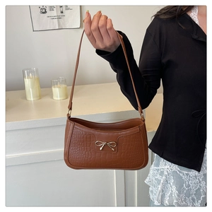 Détail du sac à bandoulière marron effet crocodile avec boucle nœud doré élégante