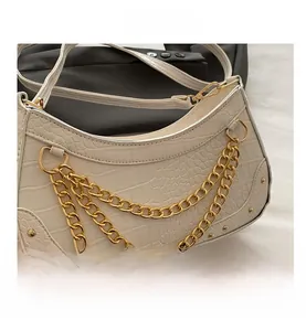 Détail du sac sous l'aisselle en cuir gaufré crocodile crème avec chaîne dorée épaisse