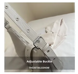 Detail of adjustable leather shoulder strap with silver metal buckle and reinforced eyelets