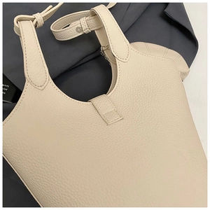 Detail of creamy white pebble grain leather bucket bag with fine stitching and dual straps