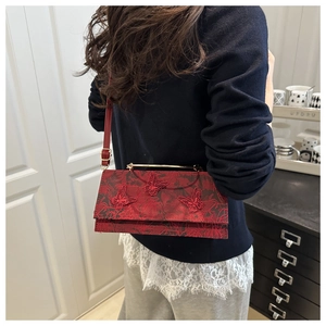 Detail of burgundy lace bag featuring 3D red butterfly appliques and gold handle