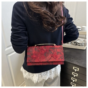 Detail of red lace crossbody bag featuring 3D butterfly embroidery and gold metal handle