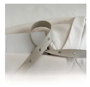 Detail of light gray textured leather shoulder strap with silver grommets and fine stitching