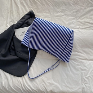 Blue and white striped canvas tote bag in a minimalist lifestyle setting on white sheets